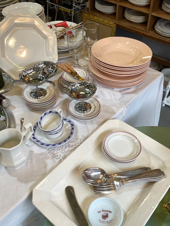 Assorted vintage tableware arranged on a table for sale in a shop.