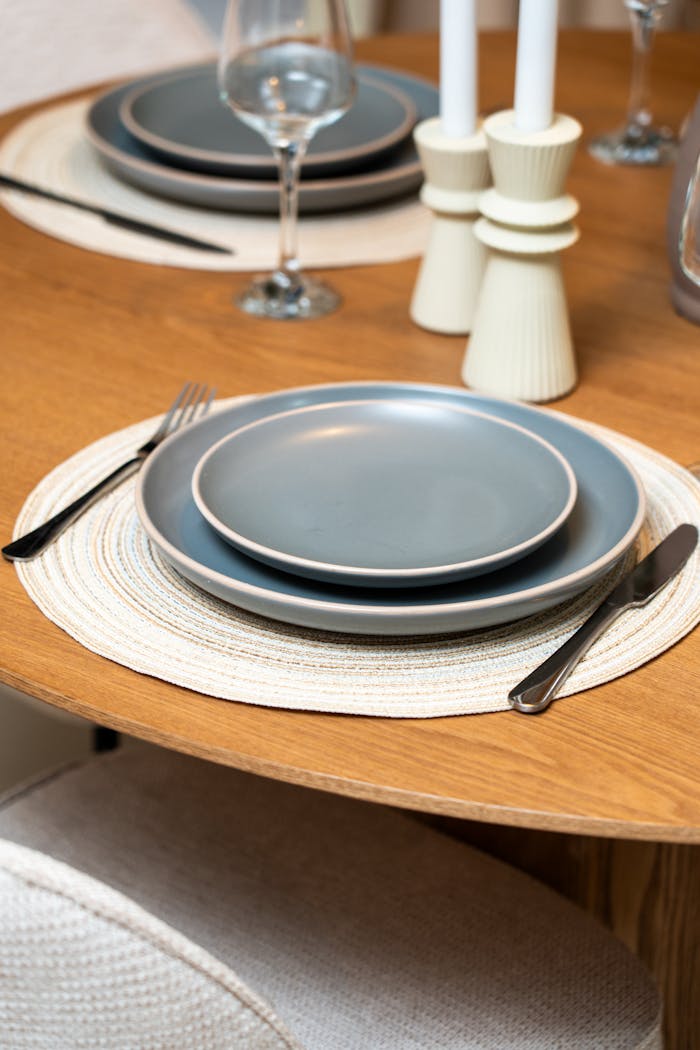 A chic table setup with blue plates, candles, and wine glasses, perfect for a modern dining experience.